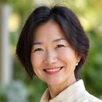 Portrait of Sofia Chan, smiling confidently in a garden setting